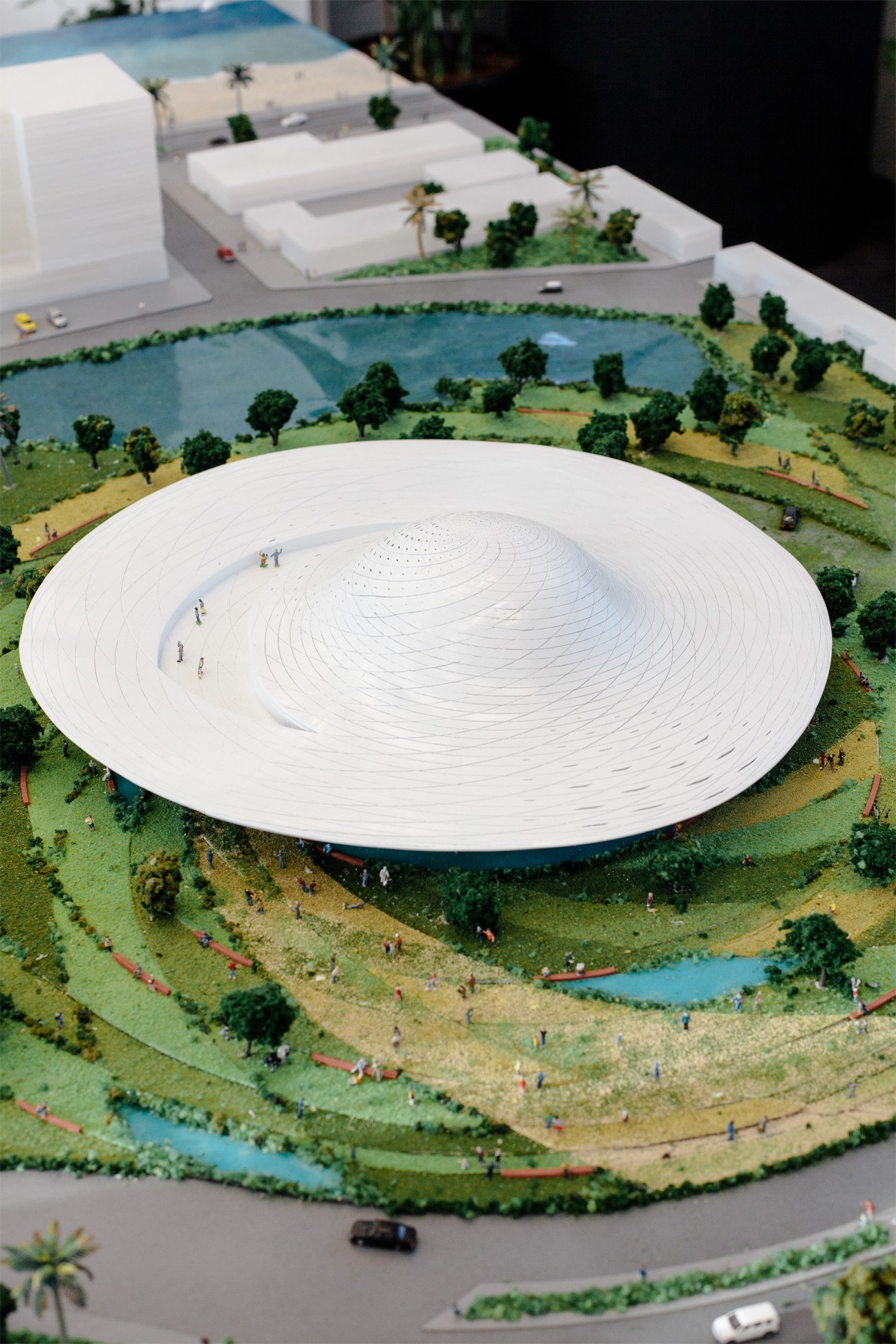 Architectural model of a circular white museum building with spiral interior design surrounded by landscaped grounds.