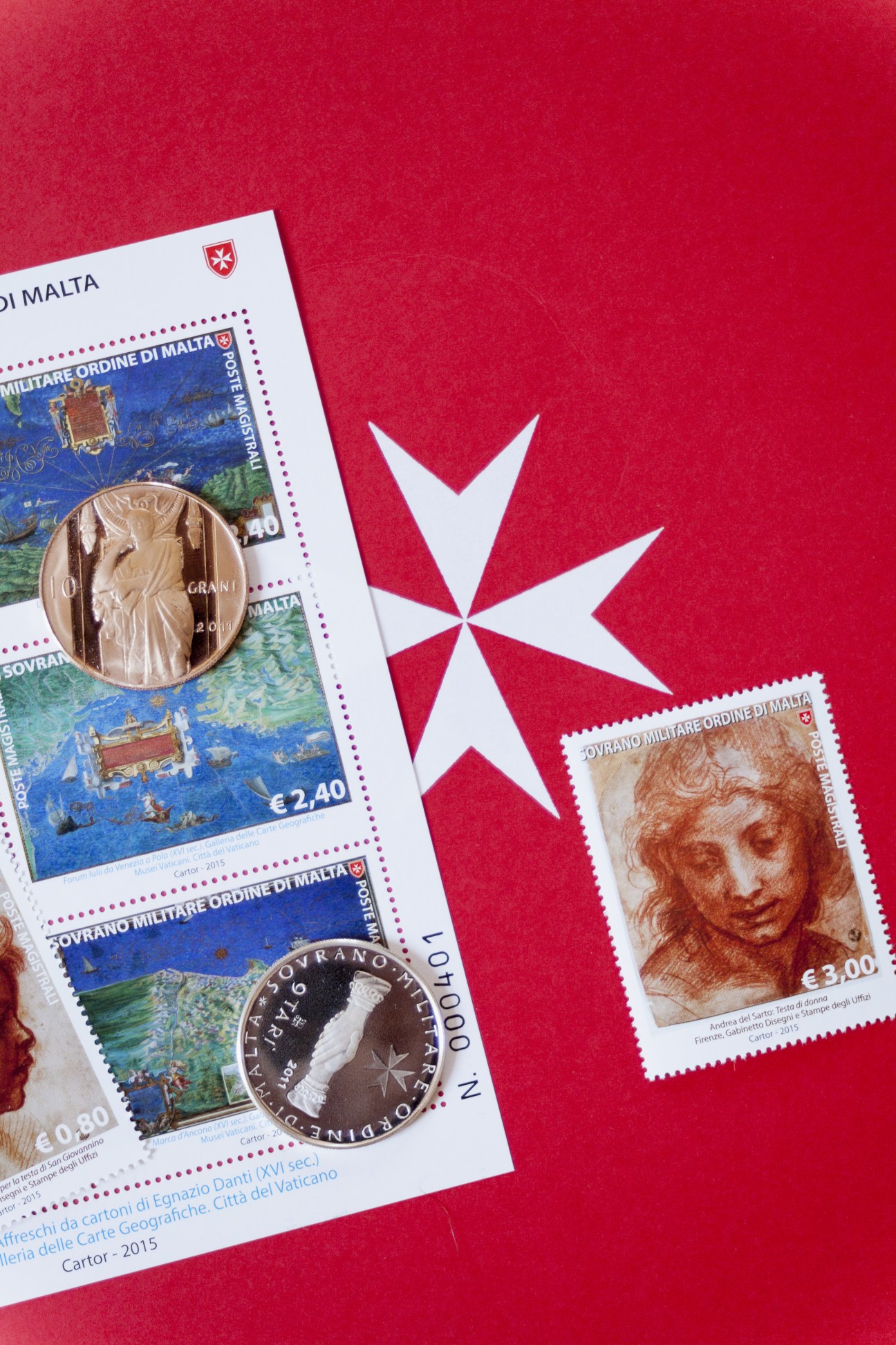 Maltese coins and stamps on red background with Maltese cross