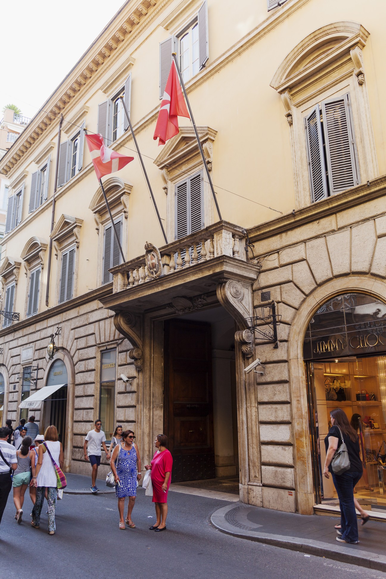 Palazzo Magistrale entrance on Via Condotti in Rome with Swiss flags and Jimmy Choo storefront visible.