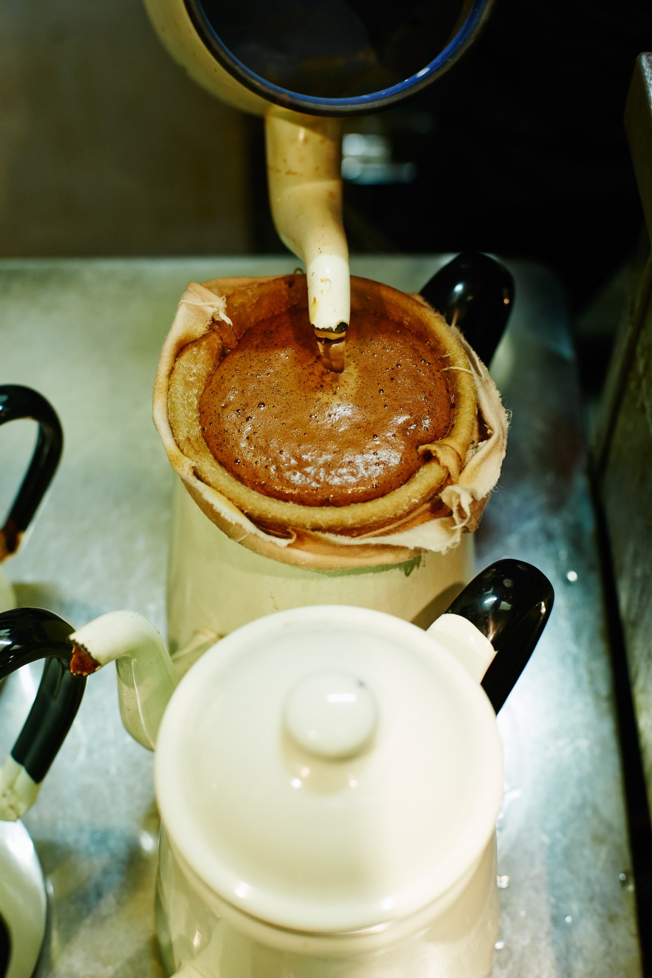 Hand-drip coffee pouring through a cloth nel filter into a cup at a Tokyo kissaten café.