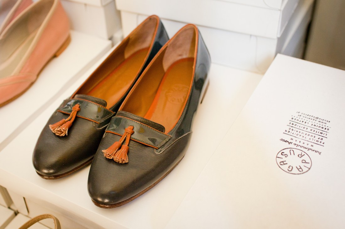 Handcrafted Aga Prus loafers with tassel details displayed on white surface next to sketches.