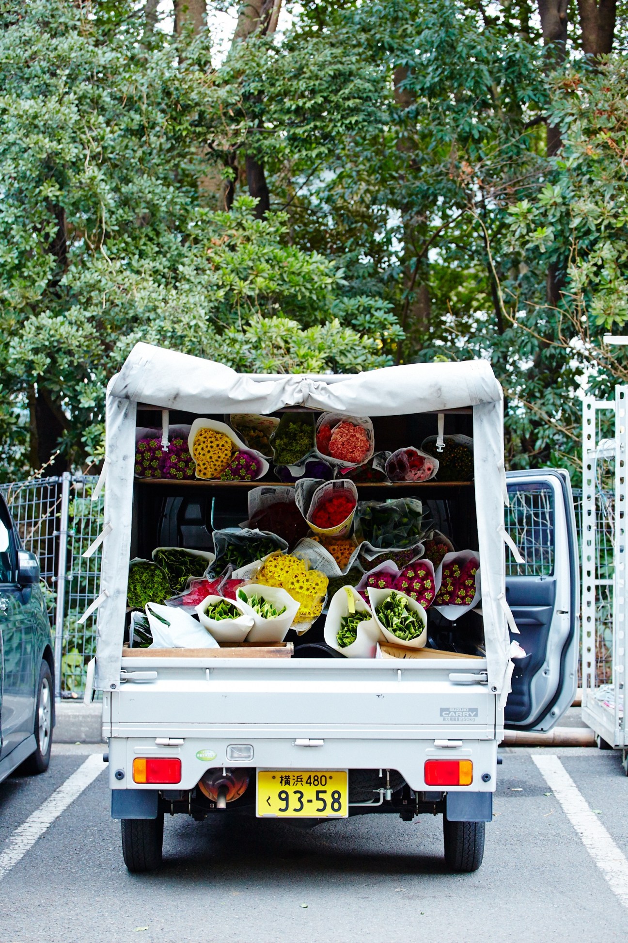 White delivery truck loaded with colorful flowers and foliage in white wrapping, heading home from Tokyo's Ota flower market.