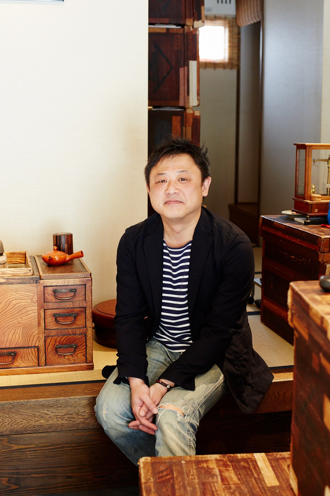 Hitoshi Akahori, founder of Maruni tea shop in Tokyo, seated in his wooden tea house surrounded by traditional wooden furniture.