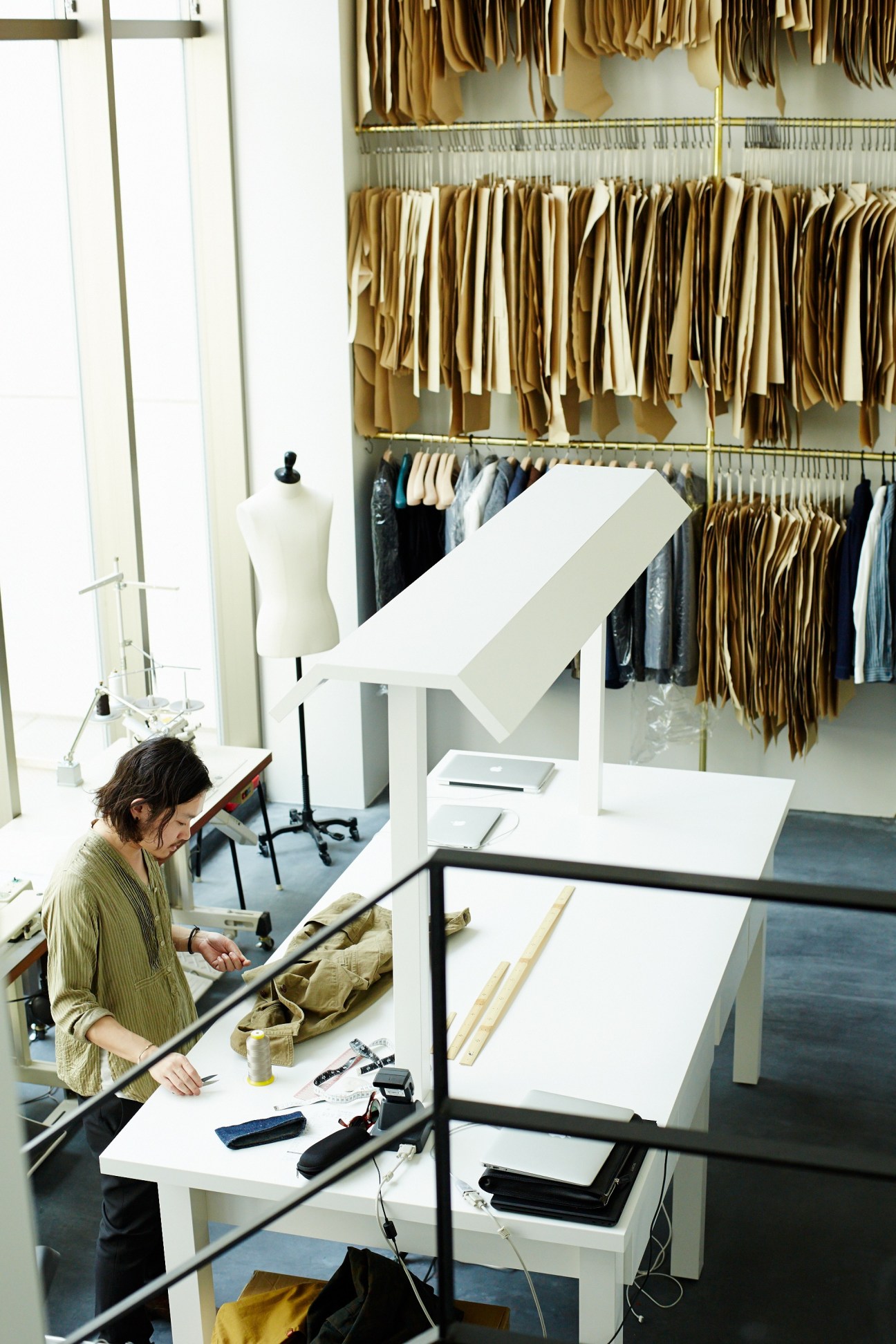 Designer working at a table in Freemans Sporting Club studio with fabric swatches hanging on walls.
