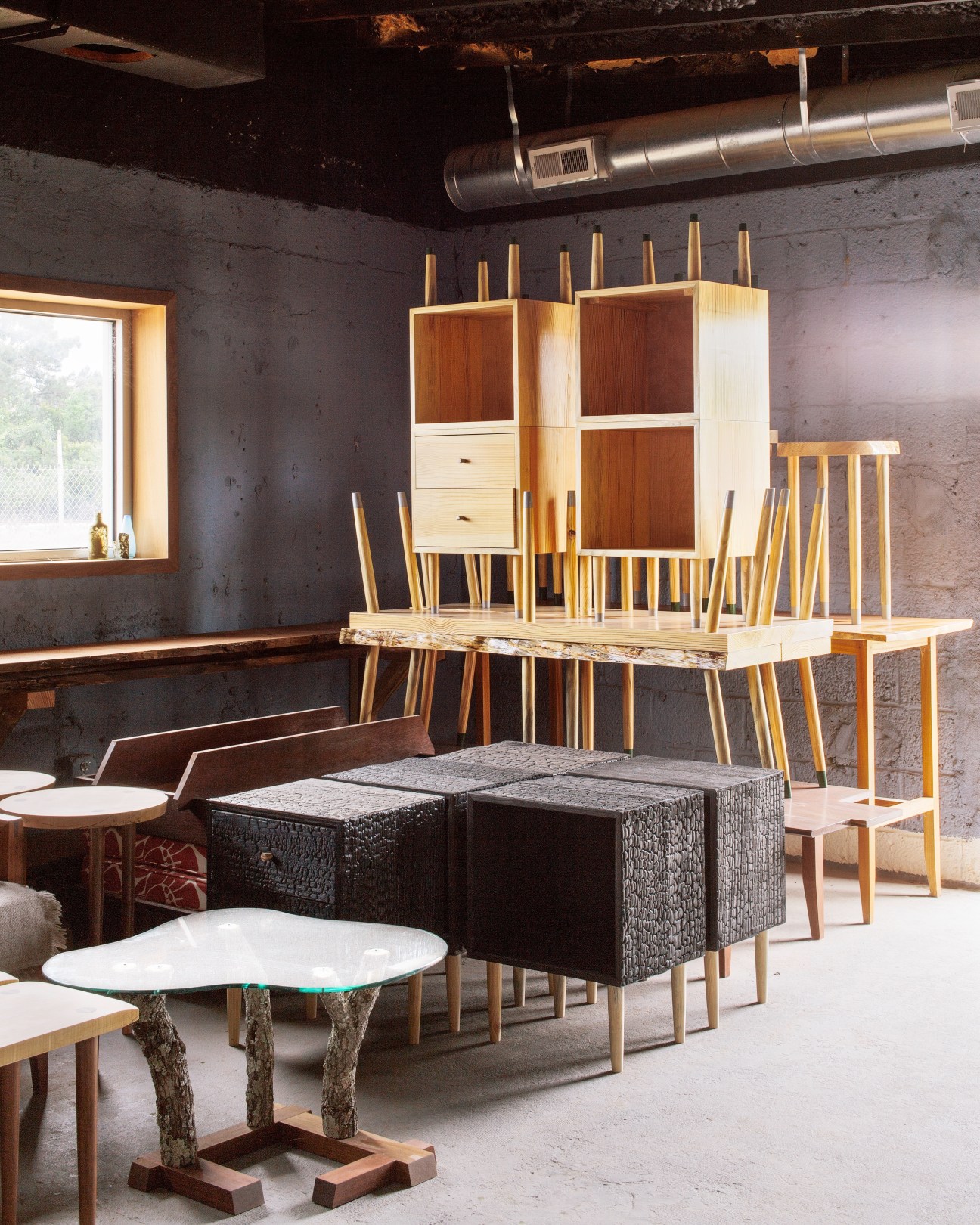 Handcrafted wooden furniture including tables, chairs, and storage units in a workshop space.