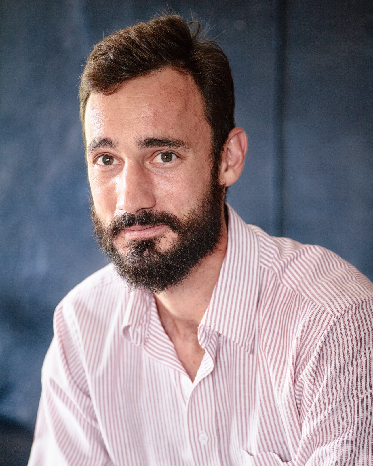 Portrait of Michael James Moran, founder of Moran Woodworked Furniture, wearing a pink striped shirt.