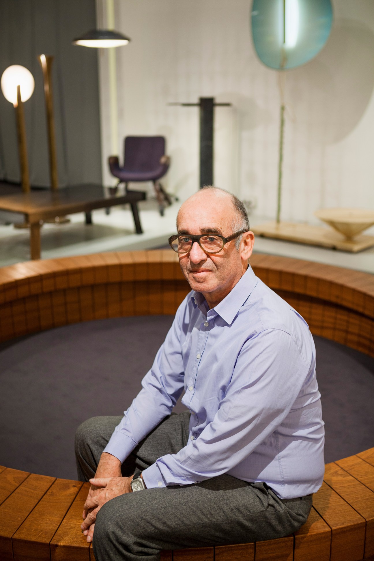 Galerie Kreo owner Didier Krzentowski sitting on a mahogany Chris Kabel Wood Ring in a modernist furniture showroom.