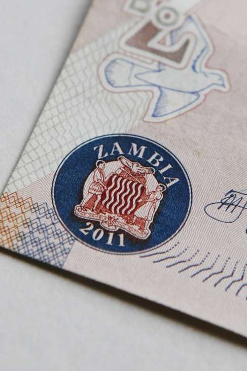 Zambia's coat of arms emblem on currency showing a man in shorts holding an axe.