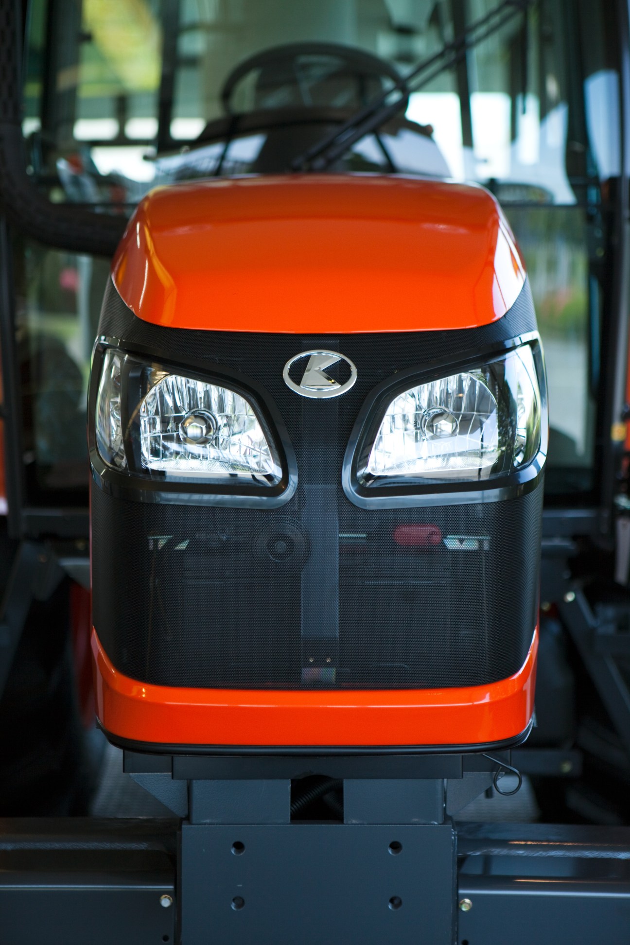 Front view of a red and black Kubota compact tractor with dual headlights and logo