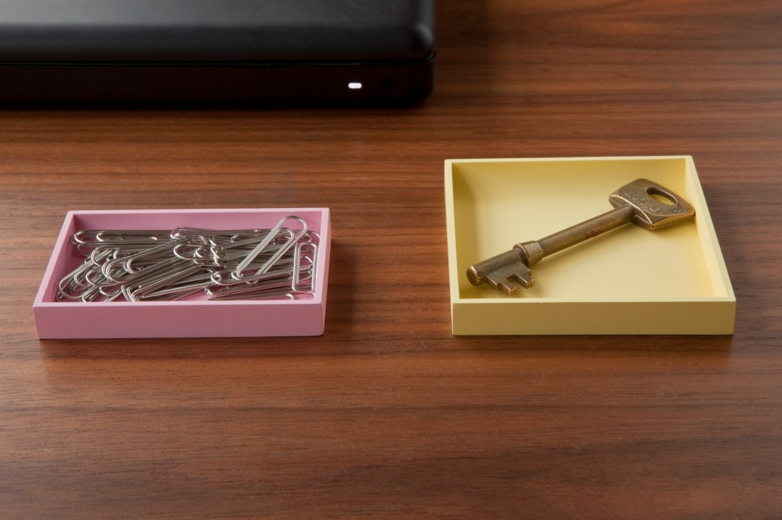 Sosuke Nakabo's stationery designs: a pink box with decorative paper clips and a yellow box with a brass key on a wooden surface.