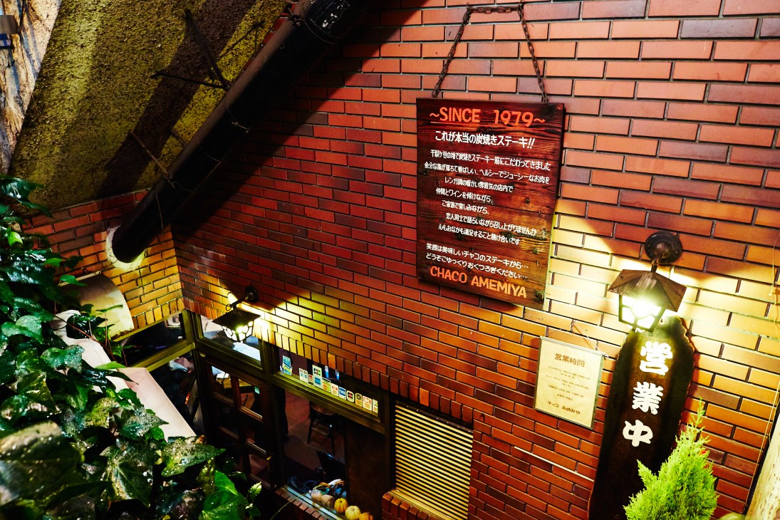 Red brick exterior of Chaco Amemiya steakhouse with illuminated signage and Japanese text.