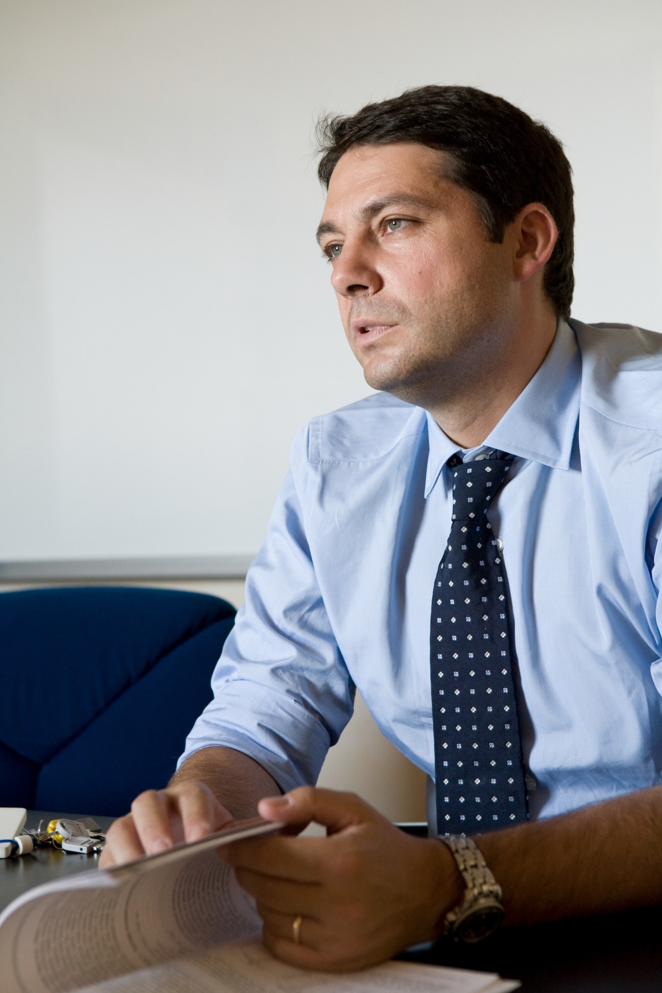 Sergio Buonanno, venture capitalist, speaks while seated at a desk wearing a light blue shirt and patterned tie.