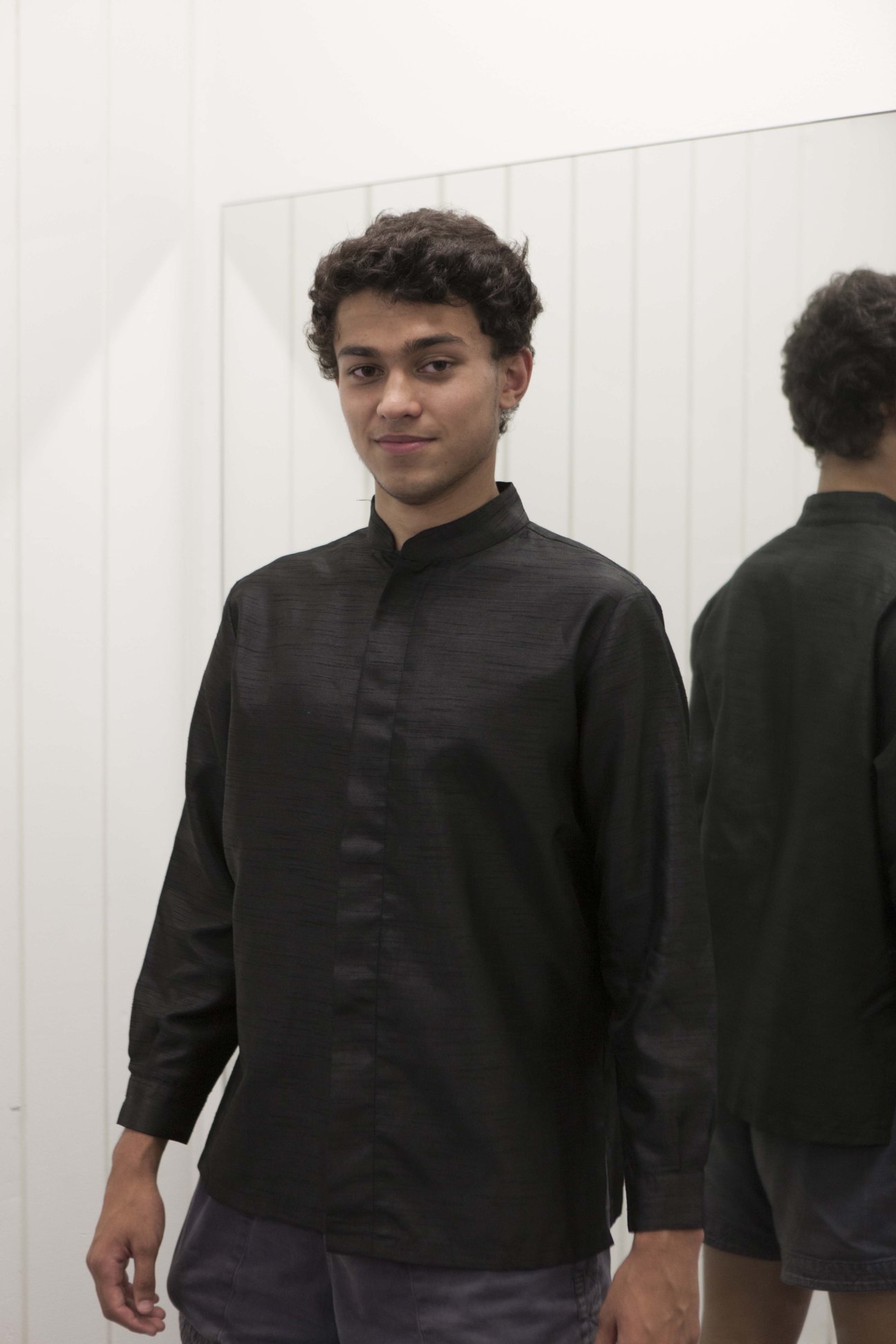Young choir member in black uniform shirt standing during rehearsal