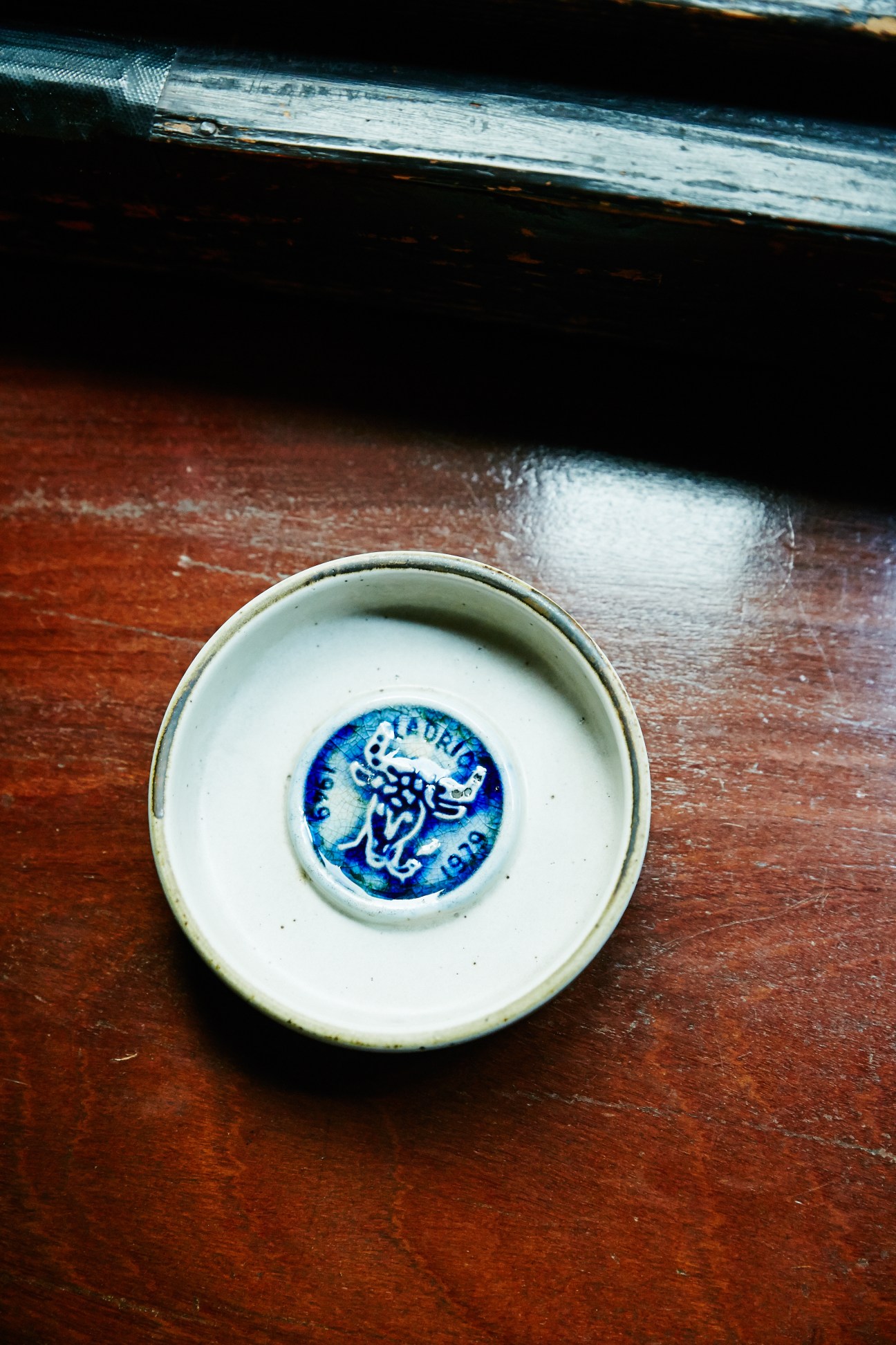 A ceramic dish with blue decorative marking on a wooden surface.