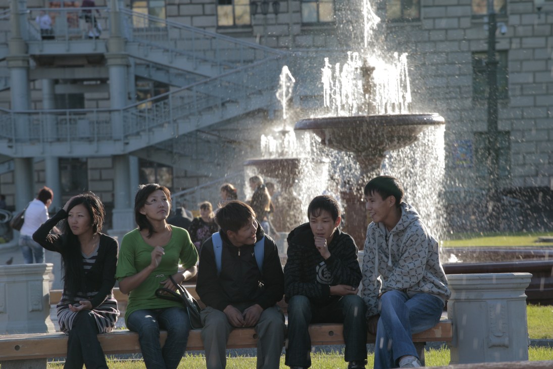 Young people sitting on a bench near a fountain in Lenin Square, Khabarovsk.