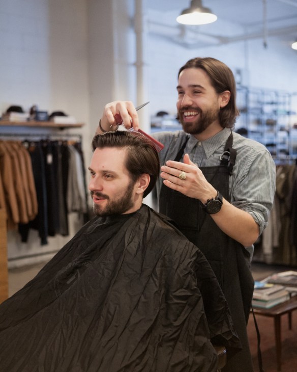 Barber Simon Chercuitte styling a customer's hair at Frank & Oak in Montreal.