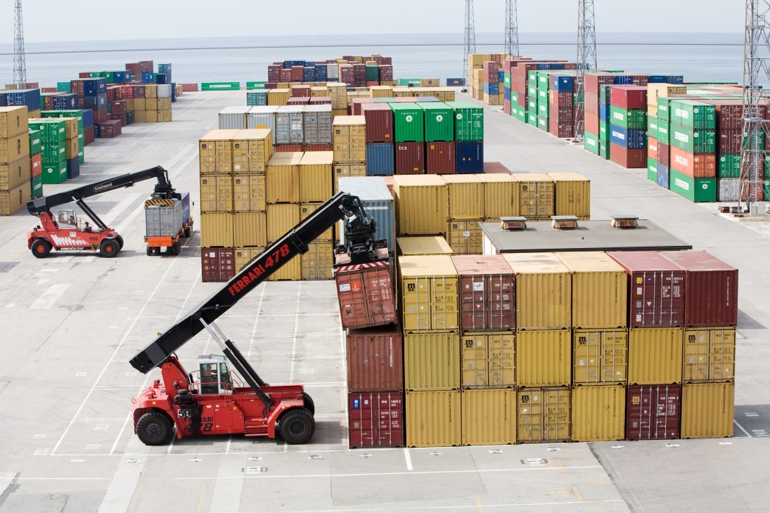 Container terminal at Pier 7 with stacked shipping containers and red cargo handling equipment.