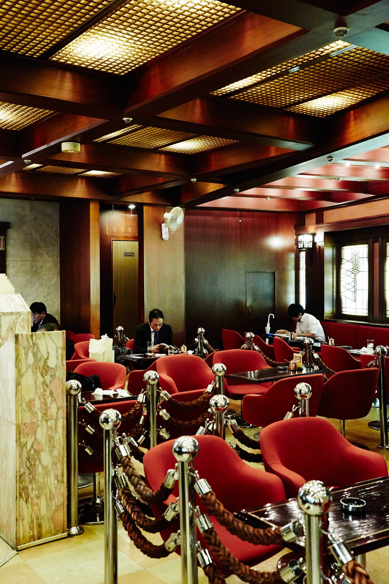 Retro interior of Royal café with red chairs, patterned ceiling, and businessmen seated at tables.