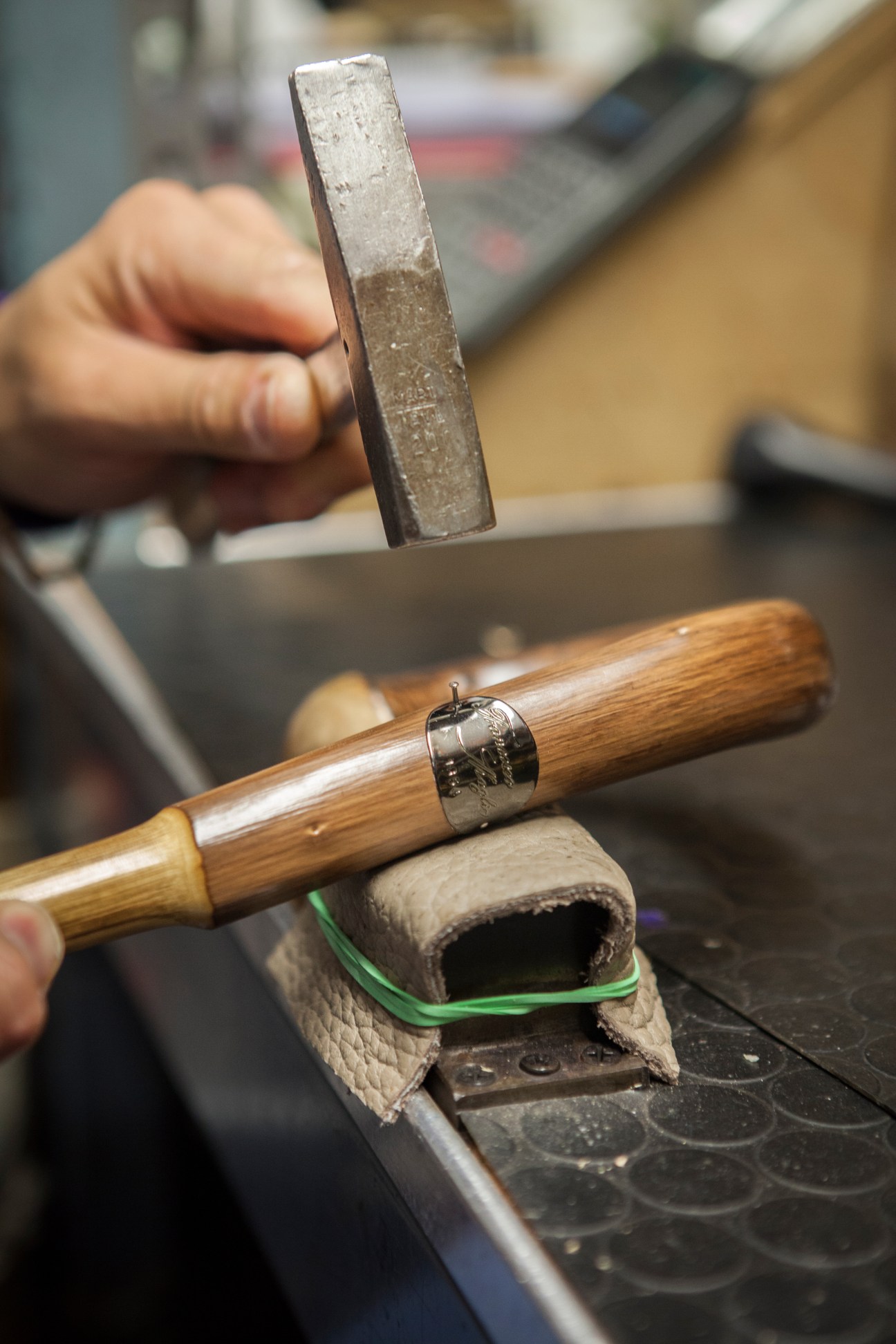 Craftsperson affixing a Maglia label to a wooden umbrella handle with metal ferrule
