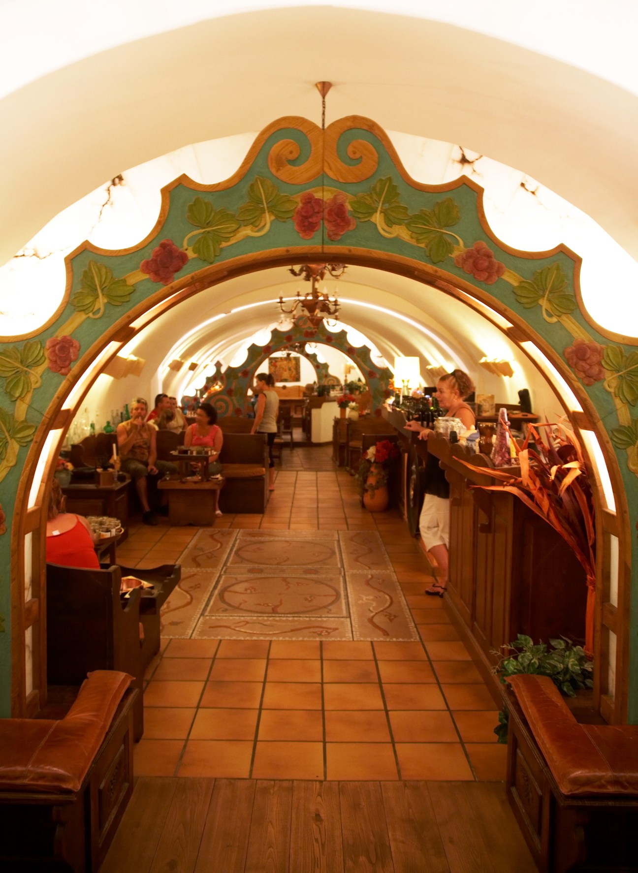 Domaine Orsini's wine cellar with ornate green and red painted archway entrance and terra cotta flooring.