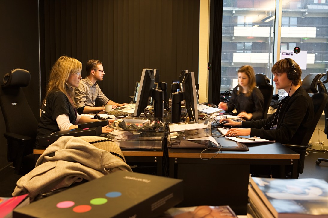 Team members working at desks in Tonium's Stockholm office with city views through windows.