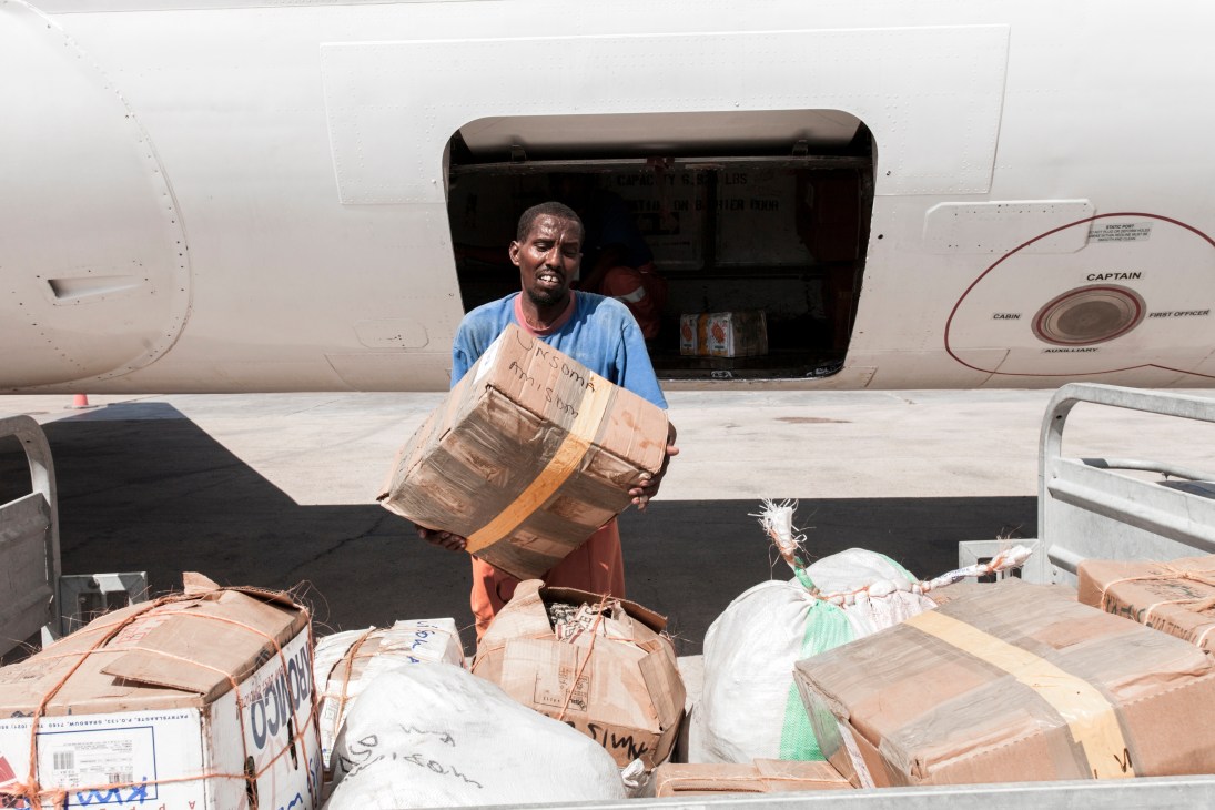 Worker unloading cargo packages from African Express aircraft at Mogadishu airport.