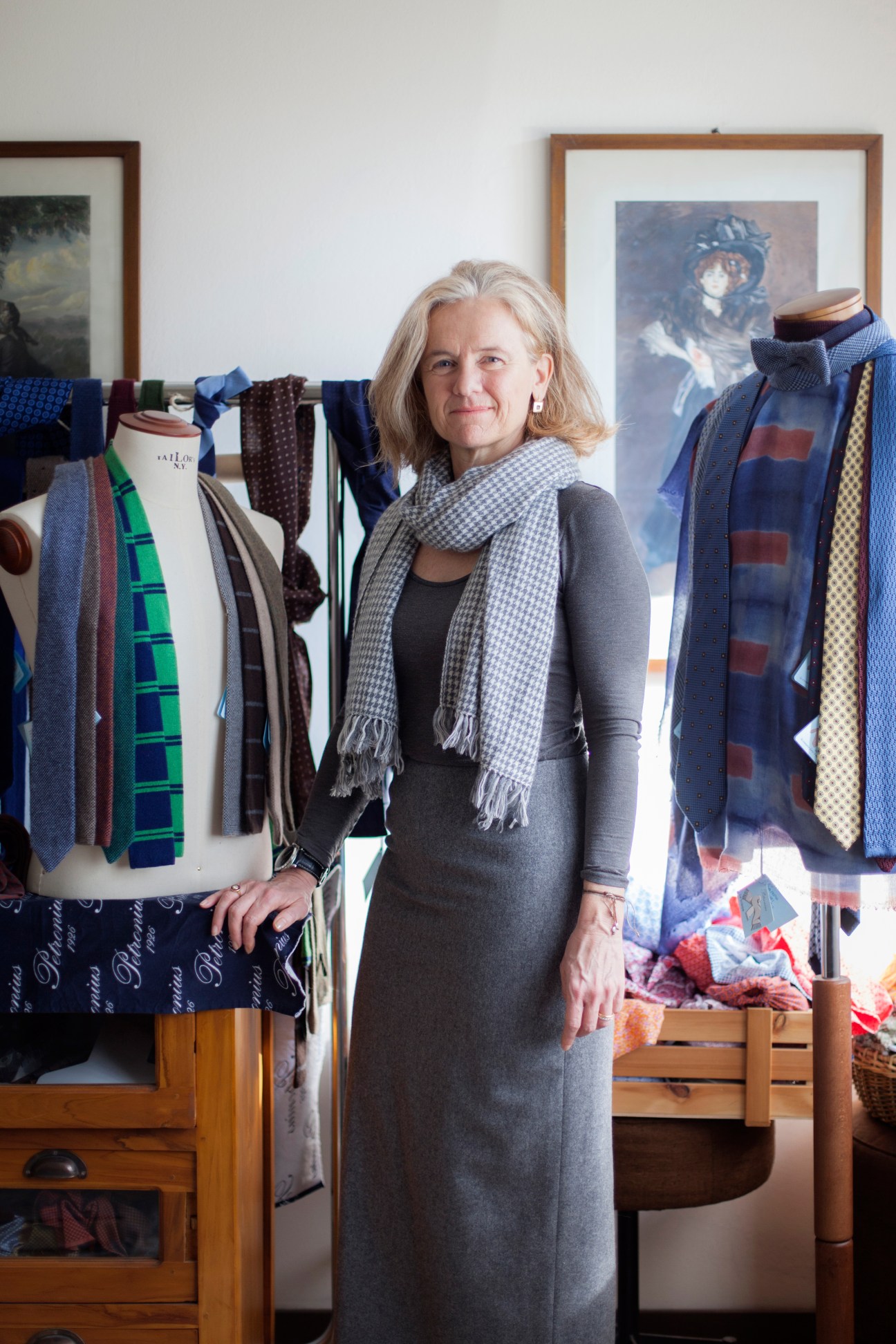Gigliola Wollisch stands in her workspace surrounded by fabric rolls and tie displays.