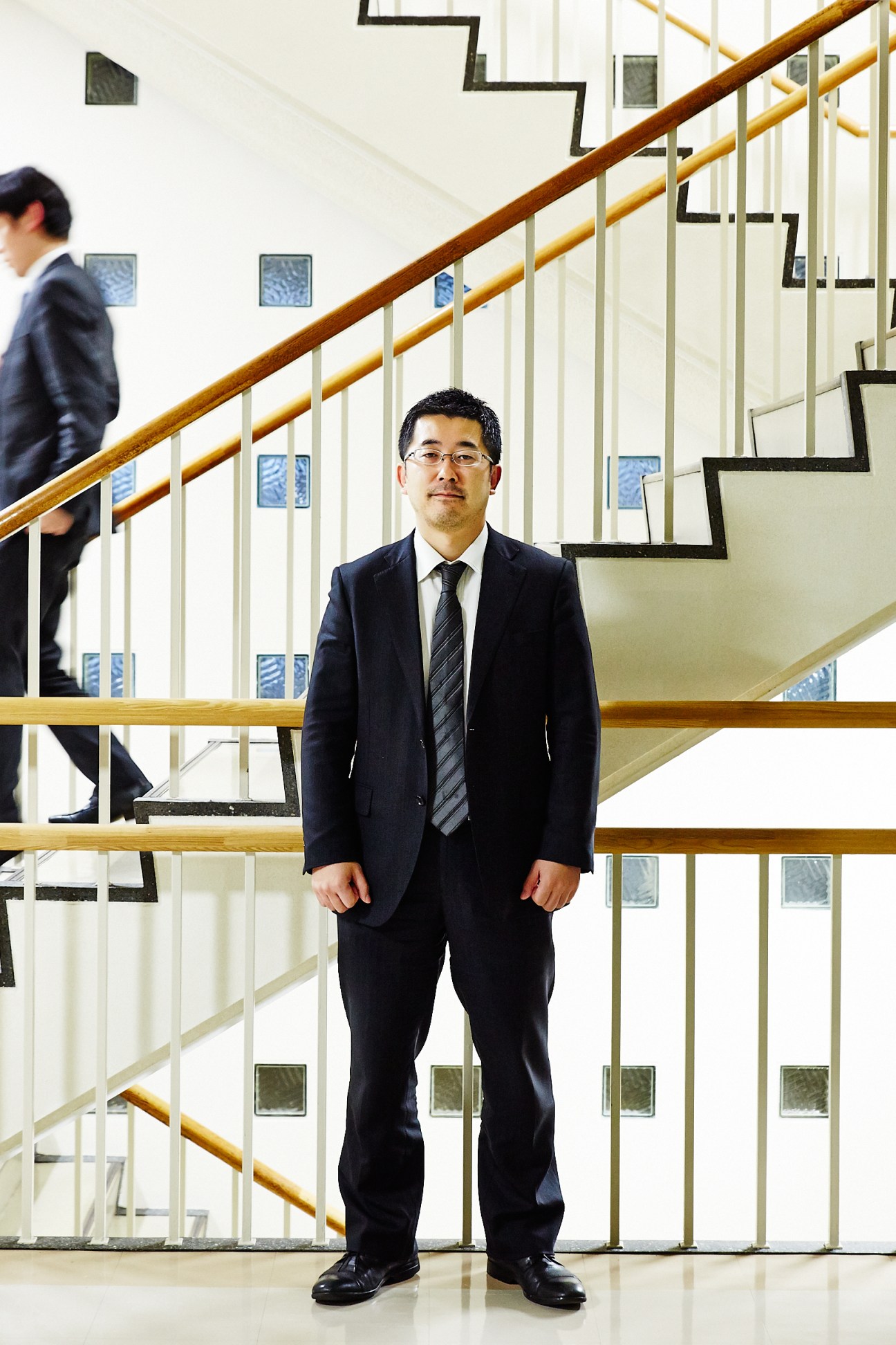 Shunichi Inoue, deputy director of Japan's Foreign Ministry China division, stands in a stairwell wearing a dark suit and tie.
