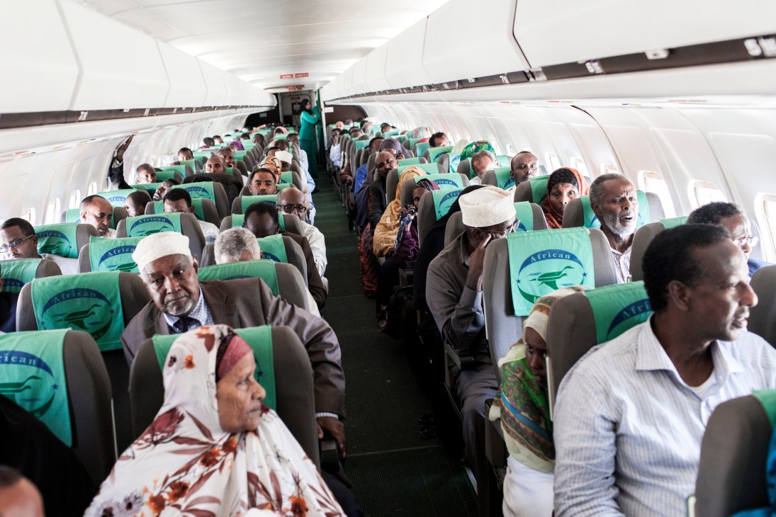 Full cabin of African Express aircraft with diverse passengers seated in green-headrested seats during boarding at Berbera airport.
