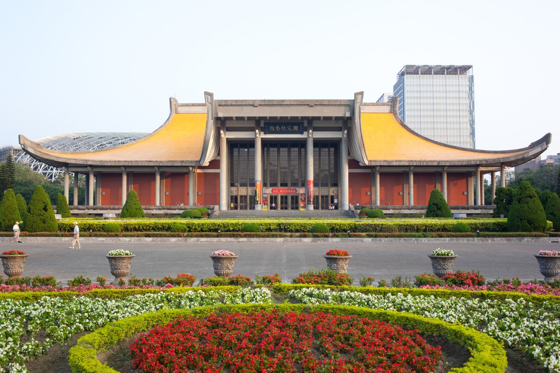 Sun Yat-sen Memorial Hall with traditional curved yellow roofs and red walls, surrounded by colorful flower beds.