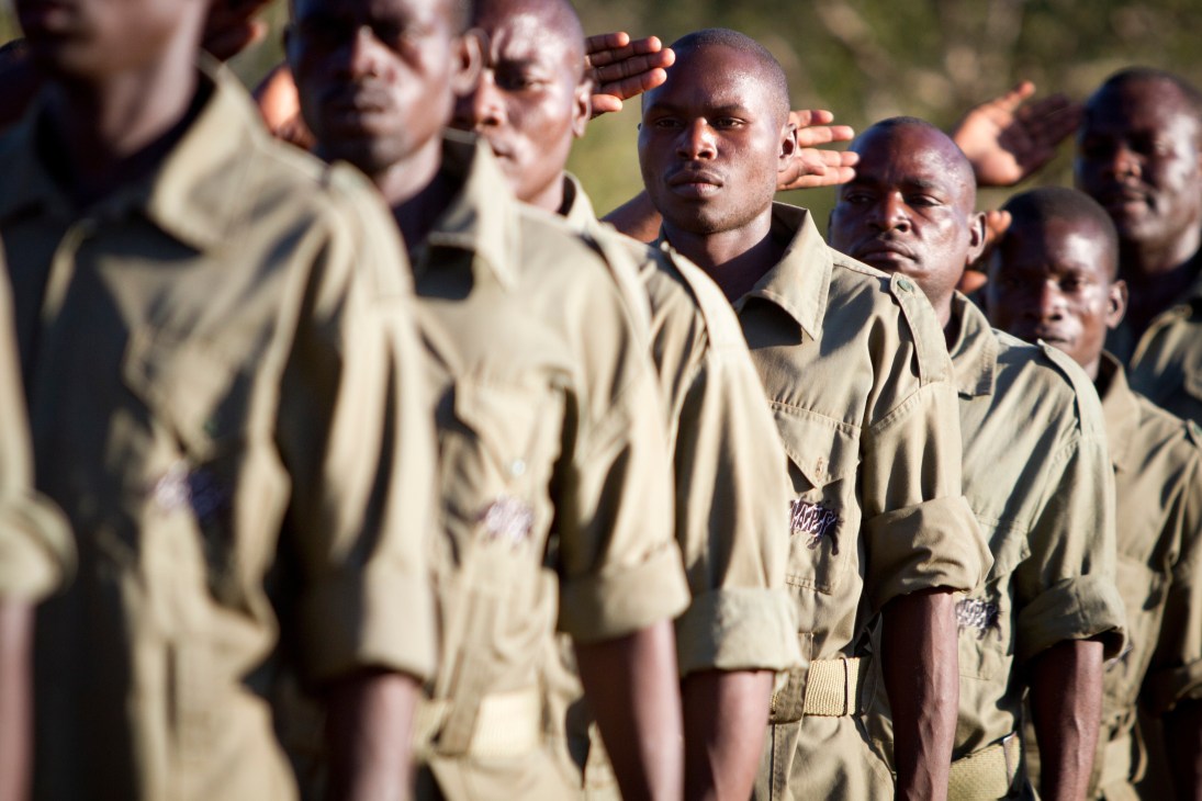 Group of anti-poaching rangers in khaki uniforms standing in formation outdoors.