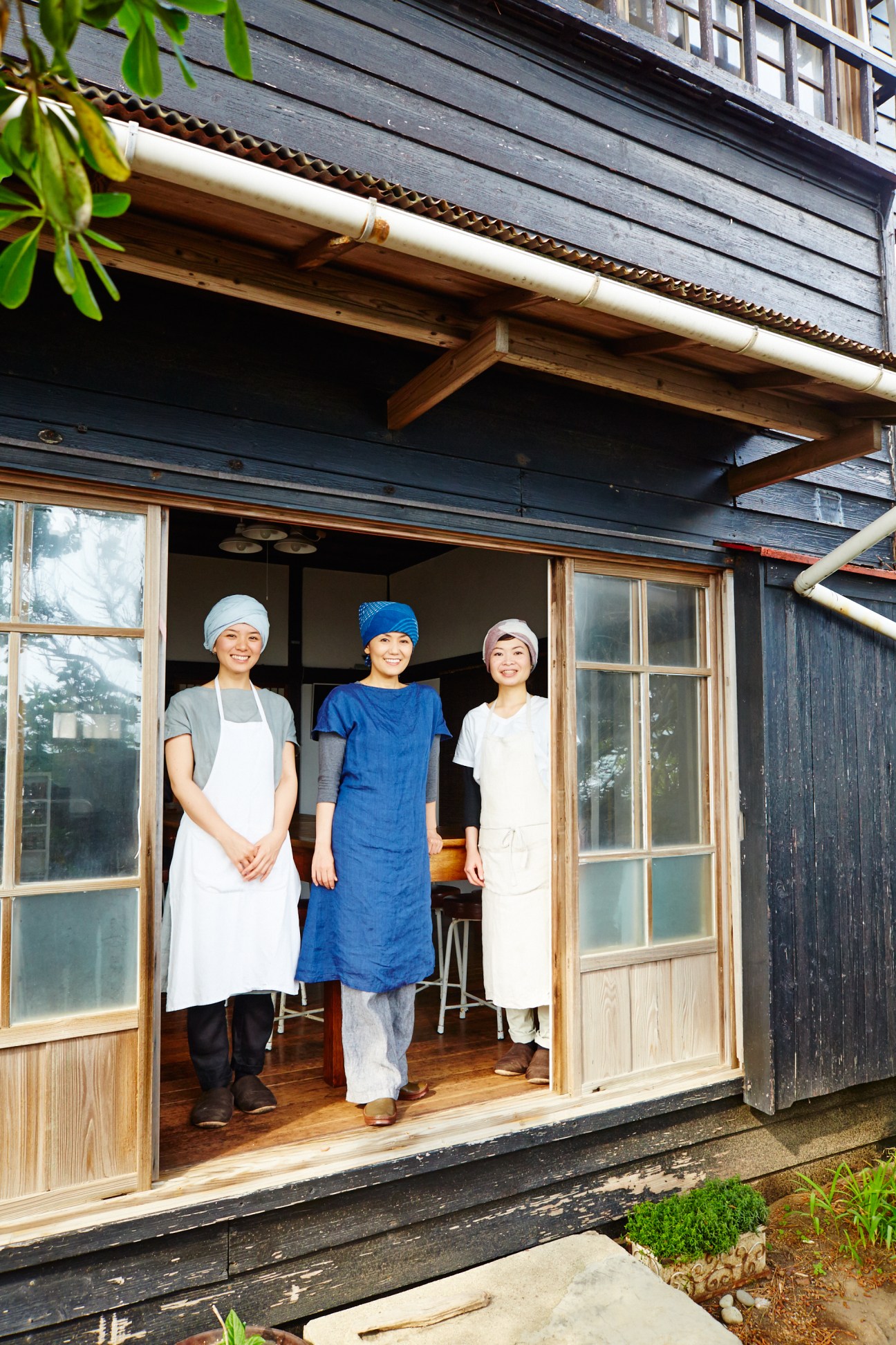 Hiroko Shirasaki and her assistants standing in the doorway of a traditional wooden building at her Hayama cooking class.