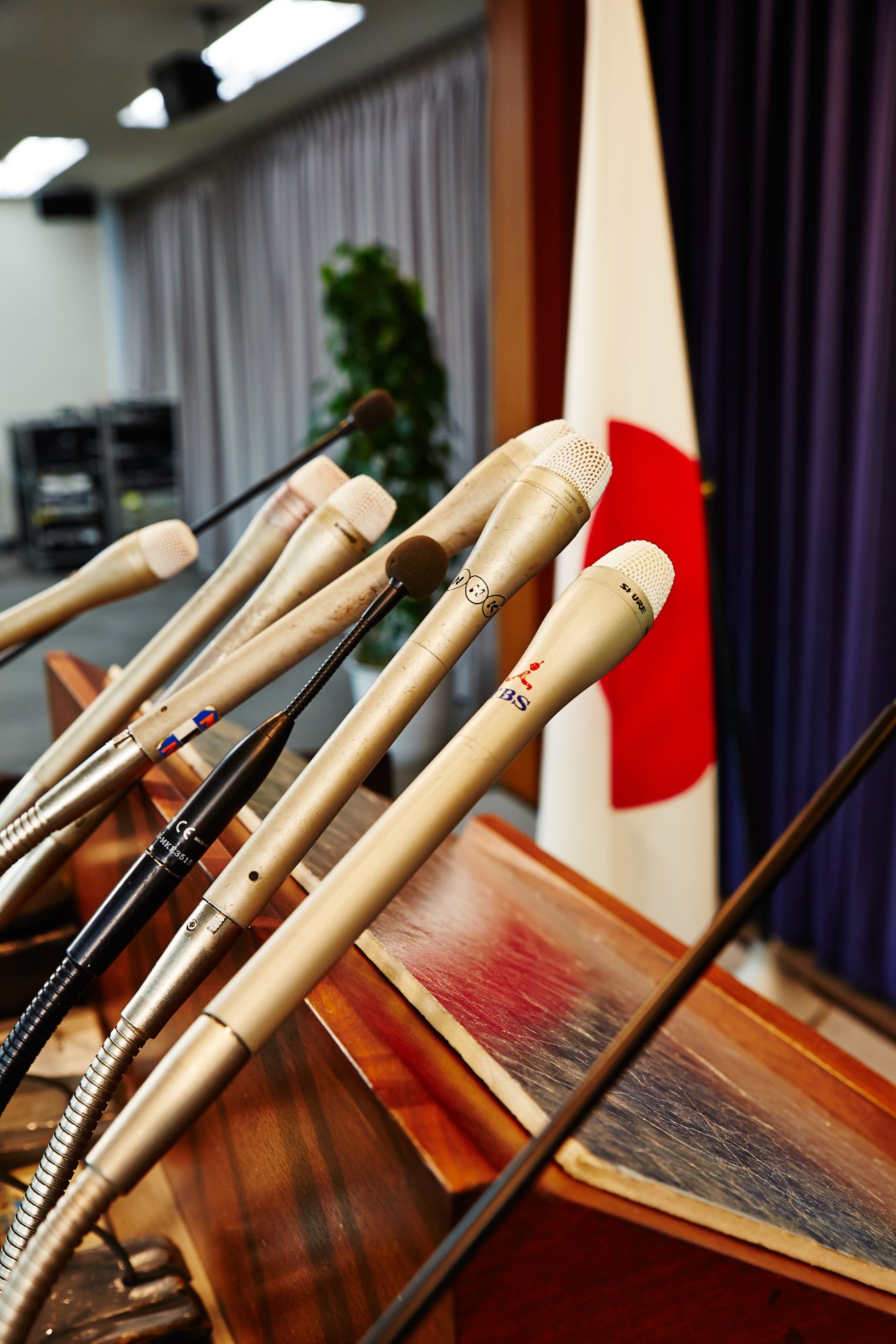 Microphones arranged on a wooden podium with the Japanese flag in the background.