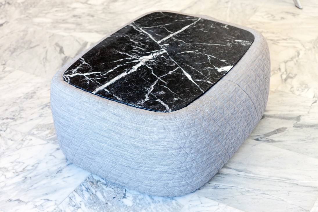 Retegui Bigun marble coffee table with black marble top and upholstered white base on marble floor.