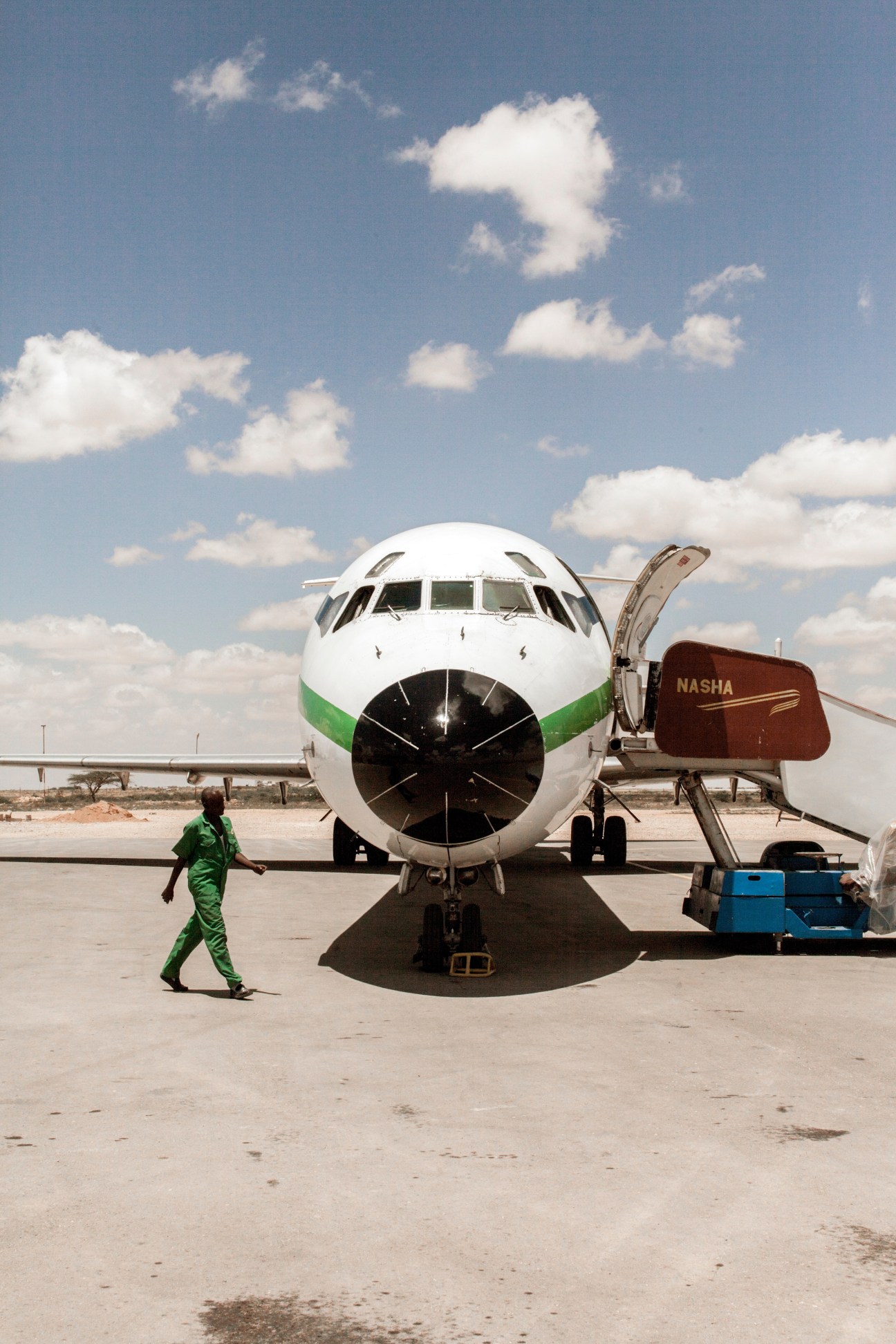 African Express MD-82 aircraft with green and white livery parked at Hargeisa airport with ground crew nearby.
