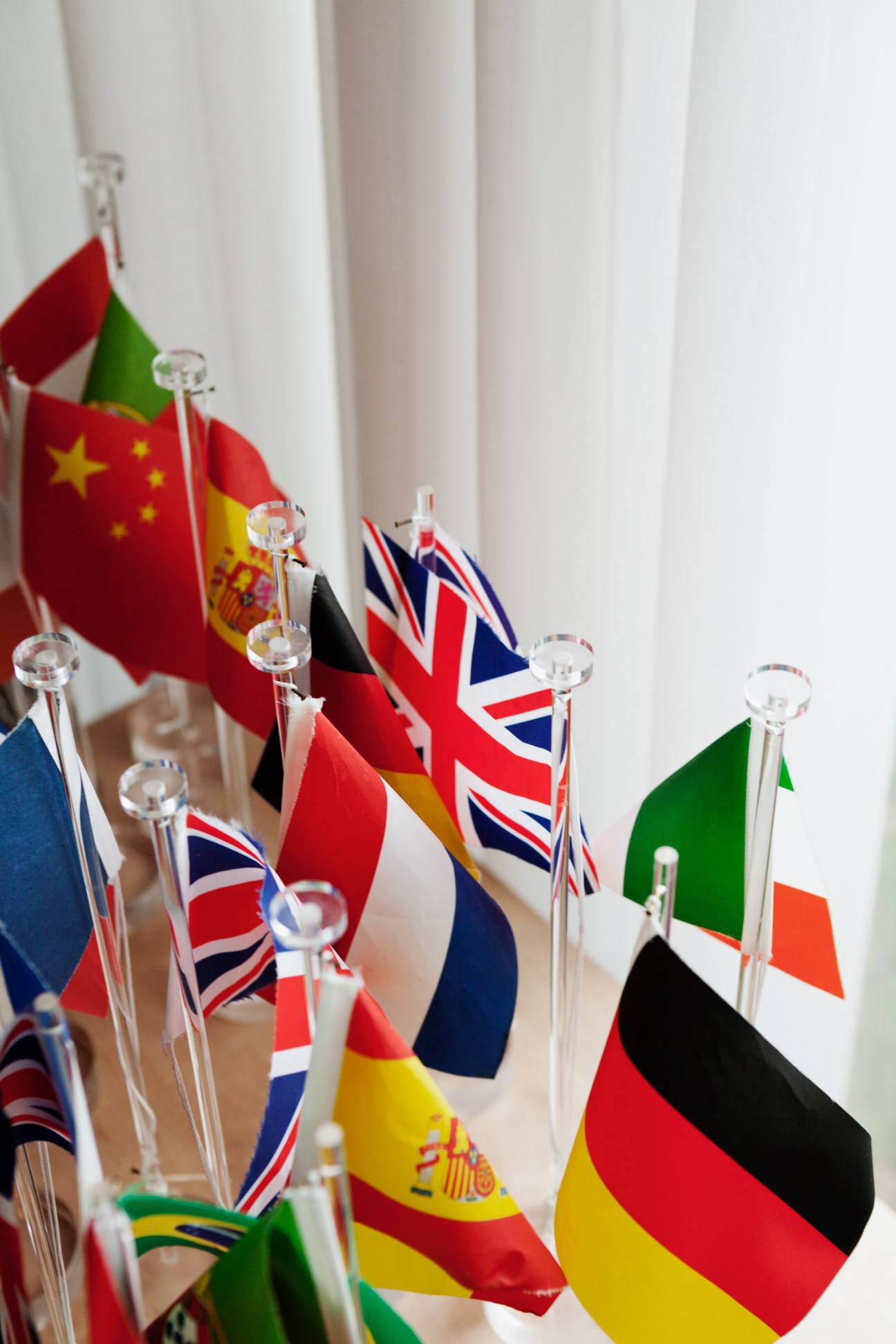 Collection of miniature international flags in clear glass holders displayed on a table.