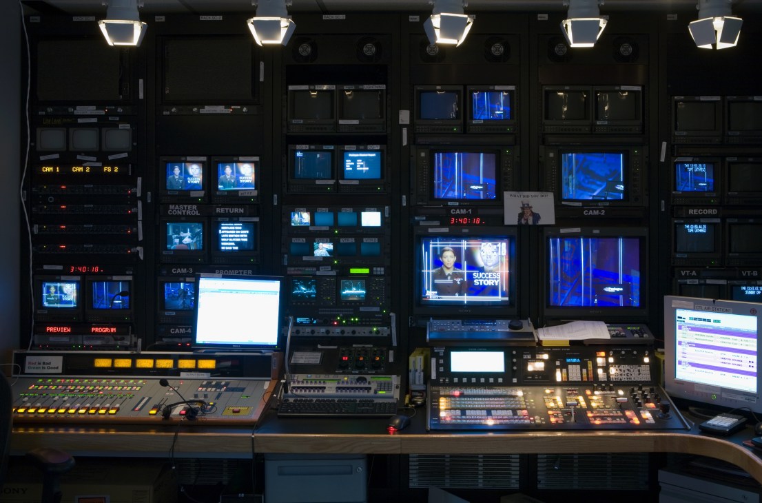 A broadcast control suite with multiple monitors displaying video feeds, control panels, and lighting equipment at the Pentagon Channel.