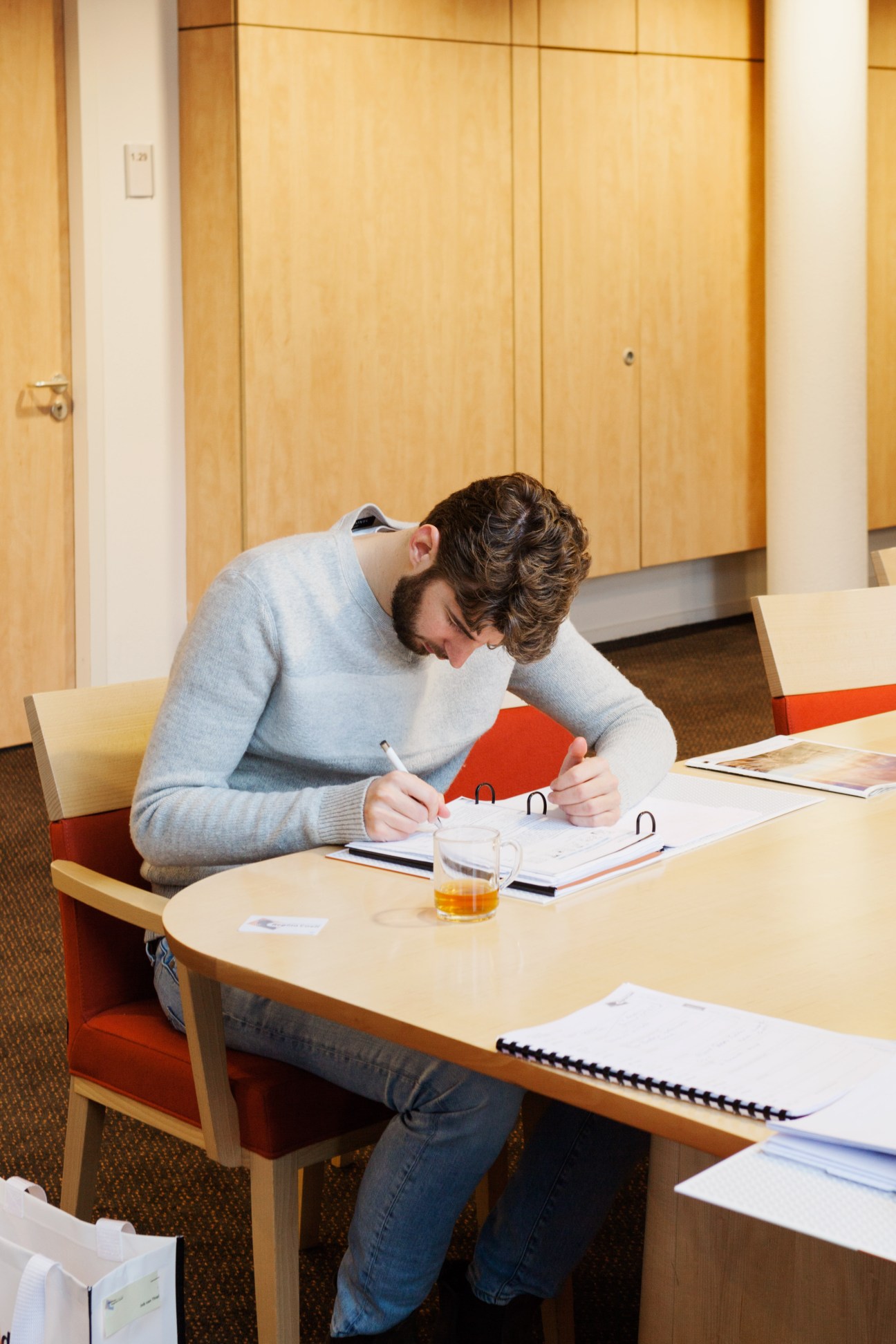 Dutch diplomat Job van Thiel studying Spanish at a wooden desk in a modern language school classroom.