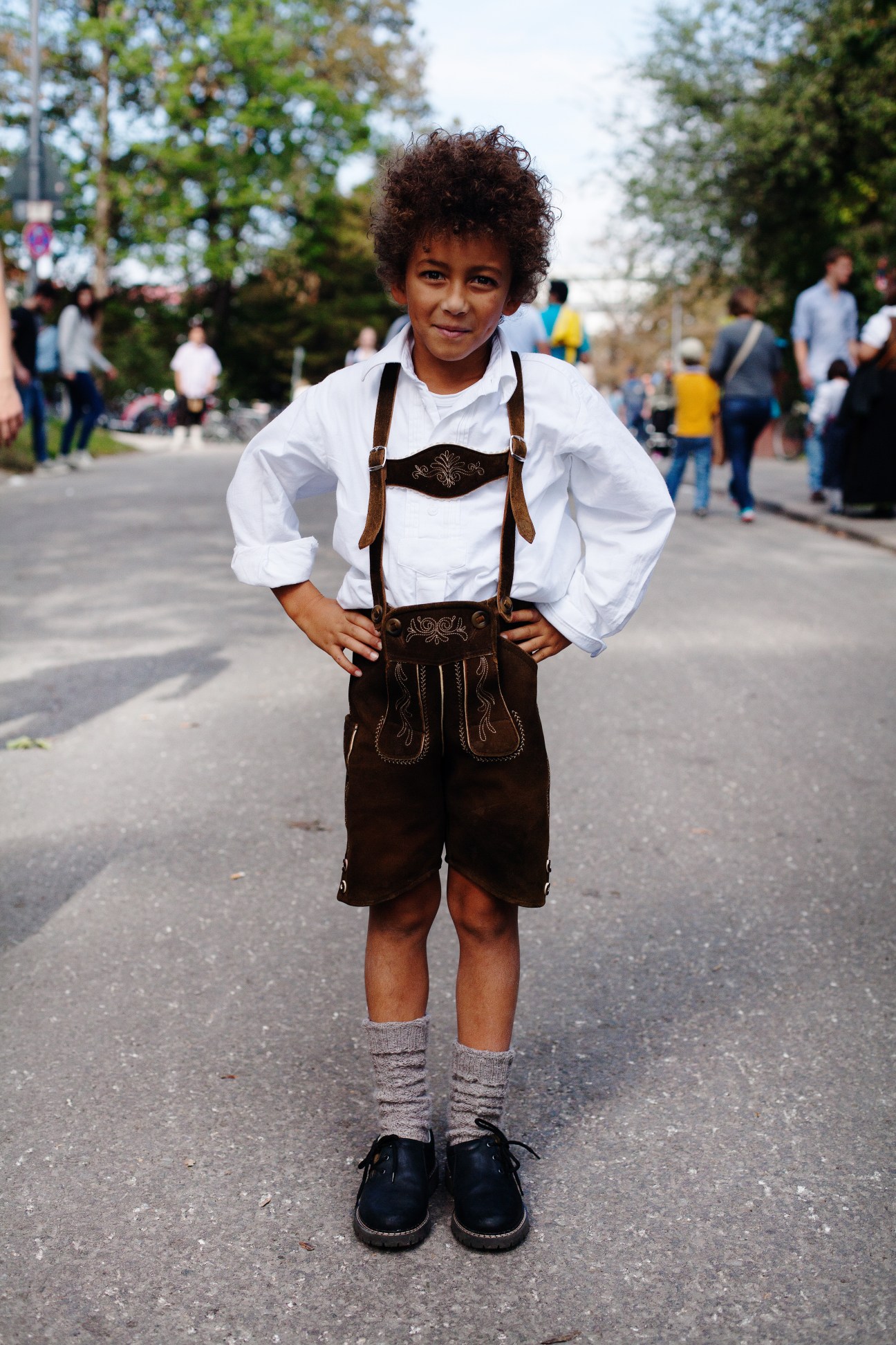 Young boy wearing traditional Bavarian lederhosen outfit with white shirt and braces at Oktoberfest.