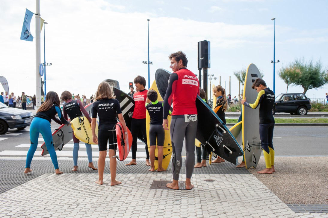Surfers with Pukas surfboards gather on a beach promenade in San Sebastián.