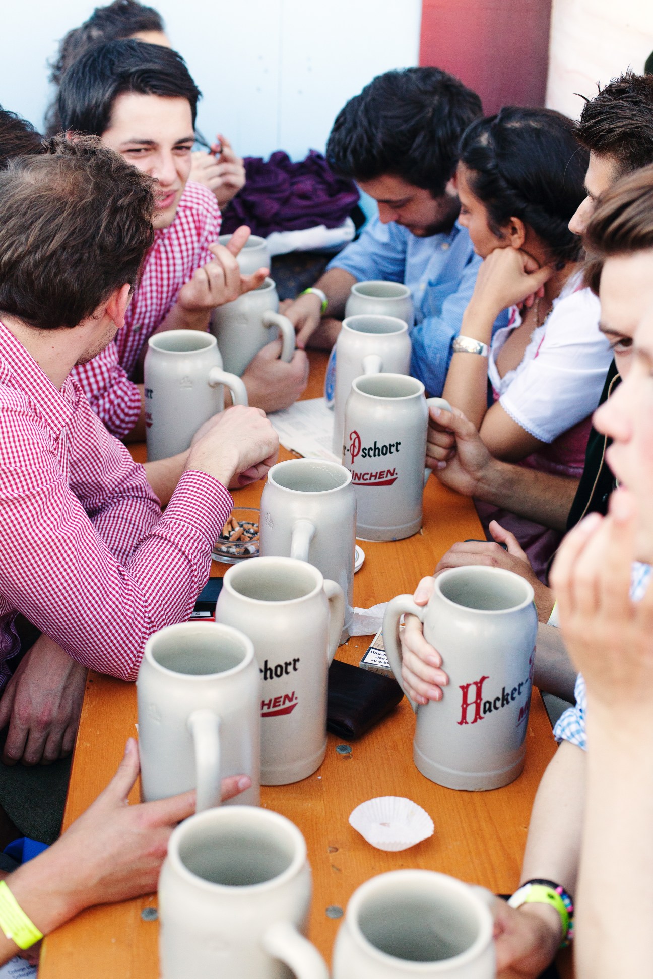 Group of people in traditional Bavarian clothing holding beer mugs at a table.