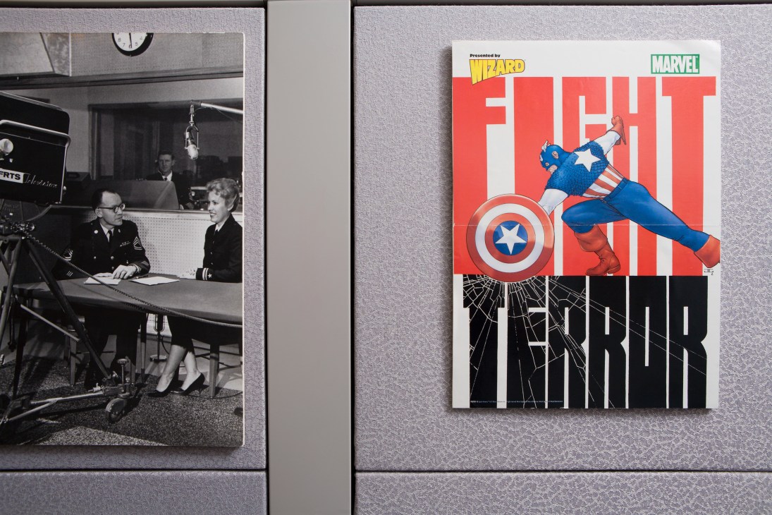 Desk display showing vintage military broadcast photo and Captain America Marvel poster.