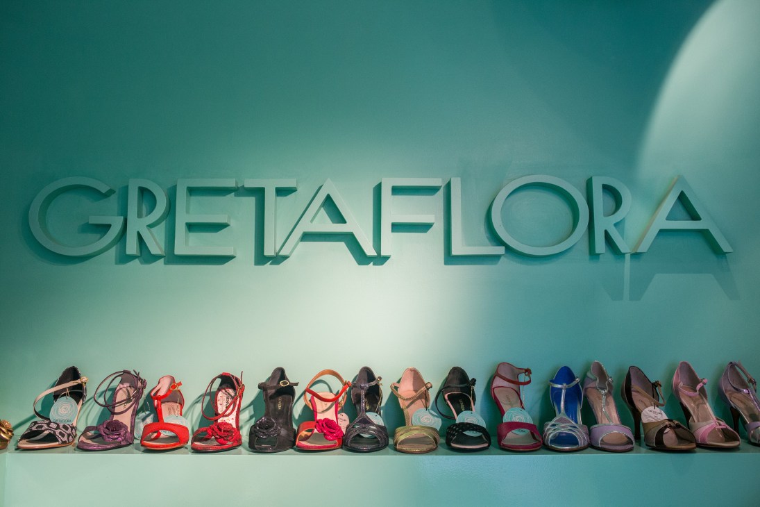 Colorful Gretaflora tango shoes displayed in a row against a teal wall with the brand name.