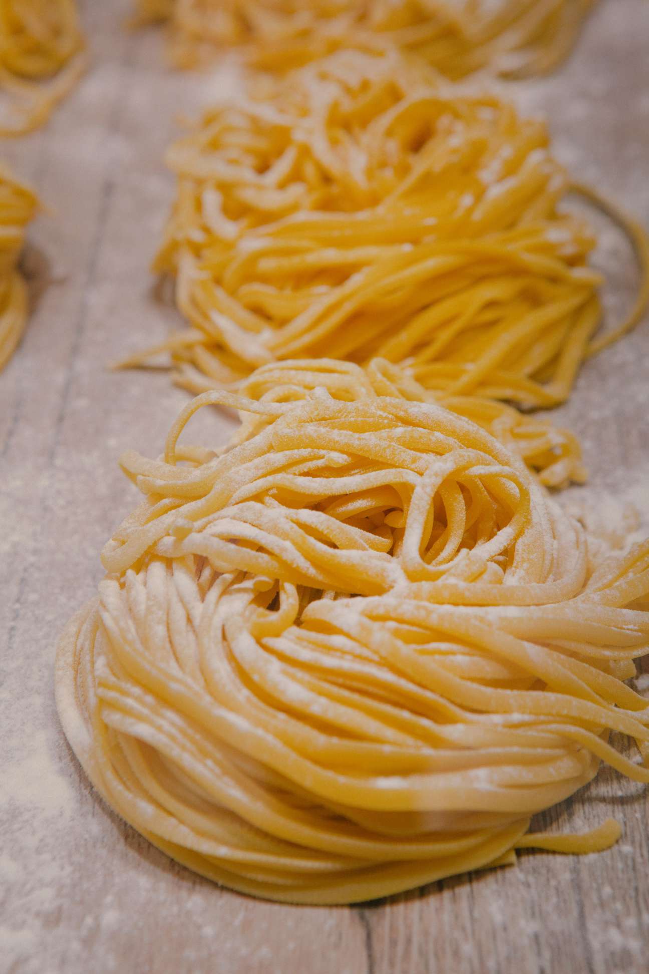 Freshly made pasta strands laid out on a wooden surface.