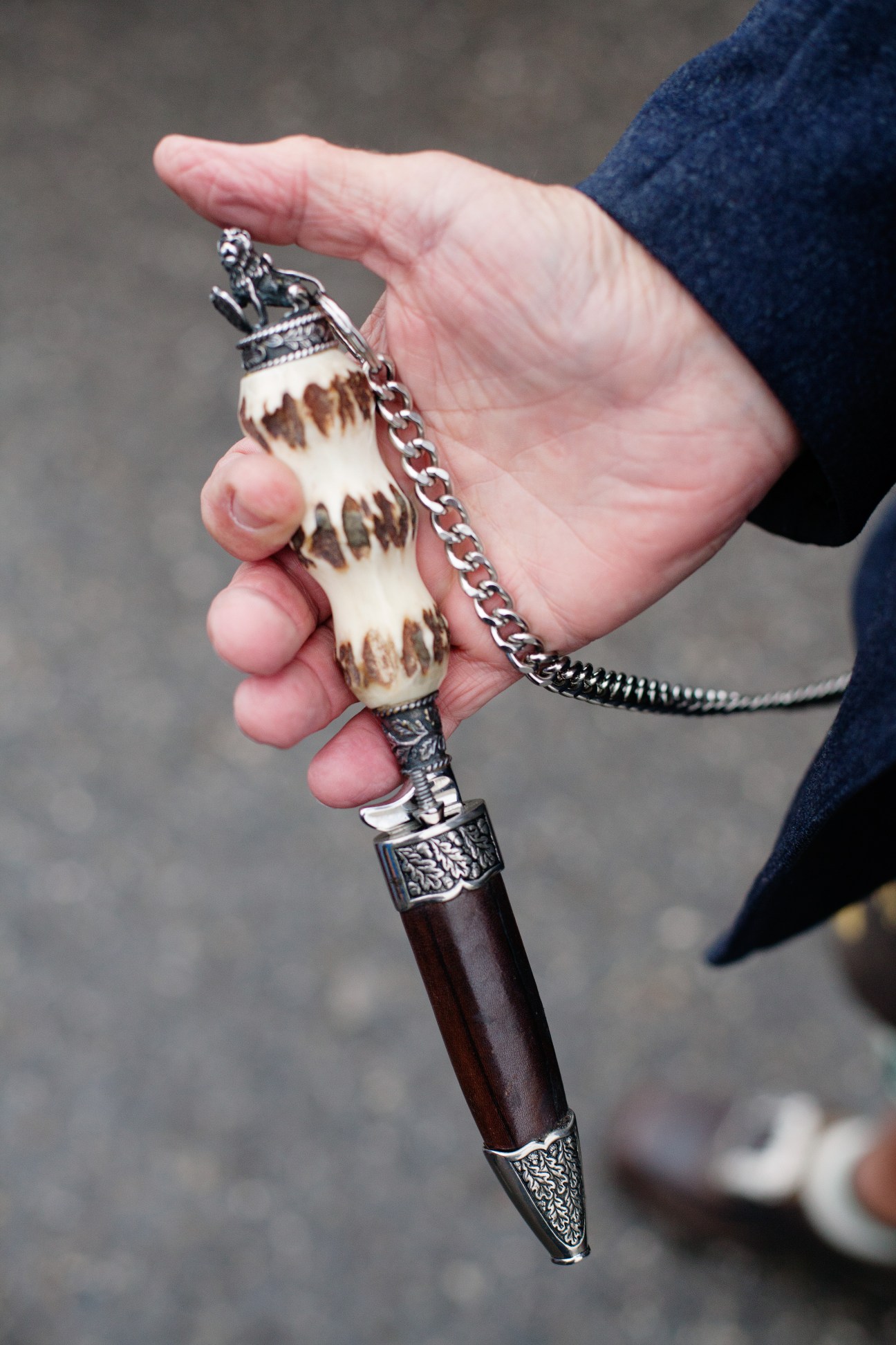 A hand holding an ornate traditional Bavarian knife with bone handle and silver metalwork on the blade.