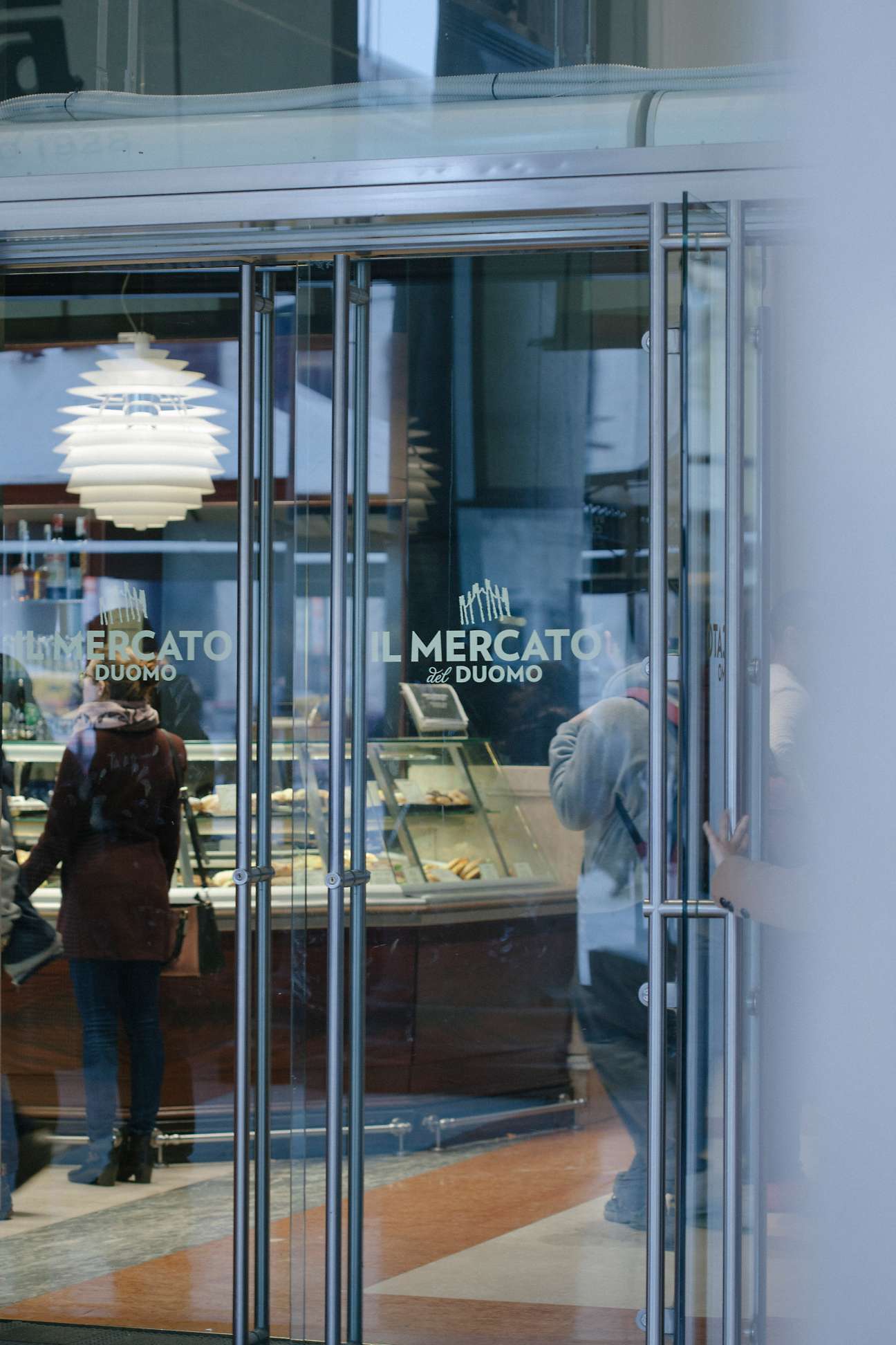 Il Mercato del Duomo storefront with glass doors and signage, showing interior displays and customers.