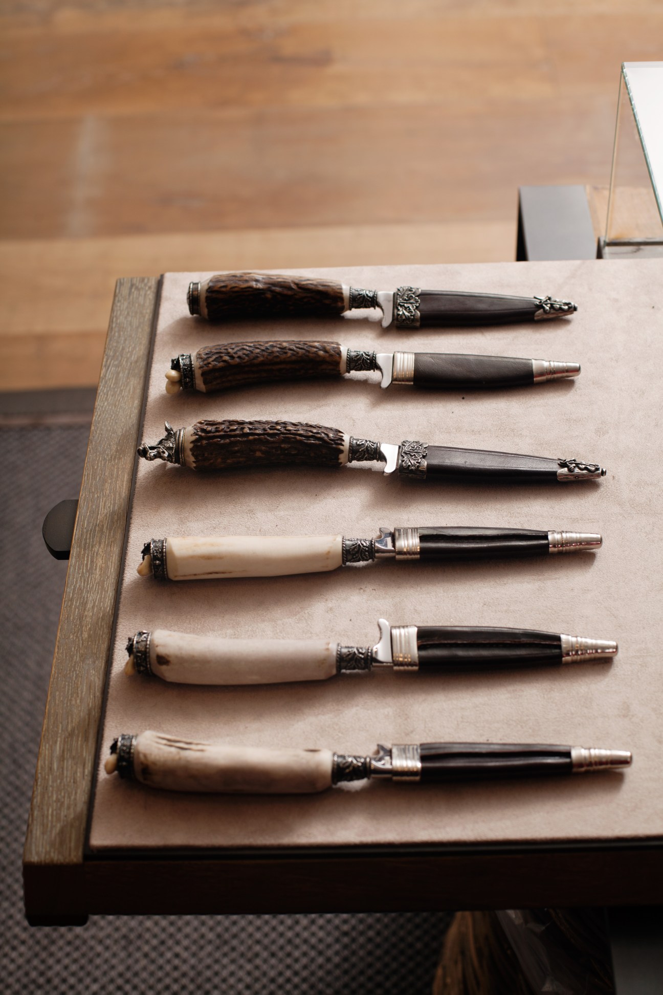 Six traditional Bavarian knives with ornate handles displayed on a wooden board at Lodenfrey.