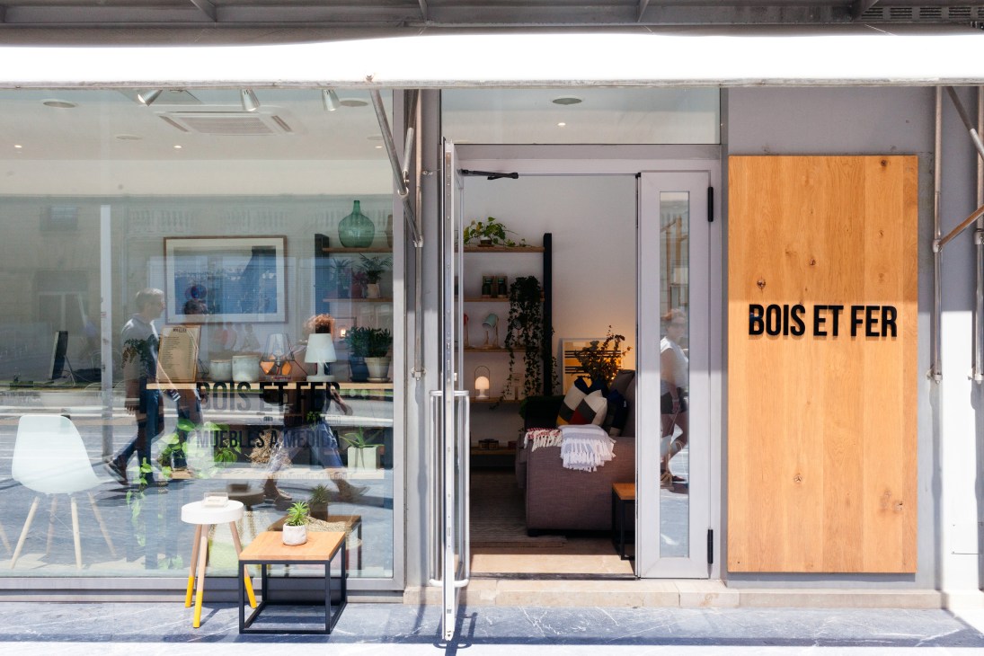 Bois Et Fer furniture design storefront with large orange wooden door and minimalist interior display in San Sebastián.