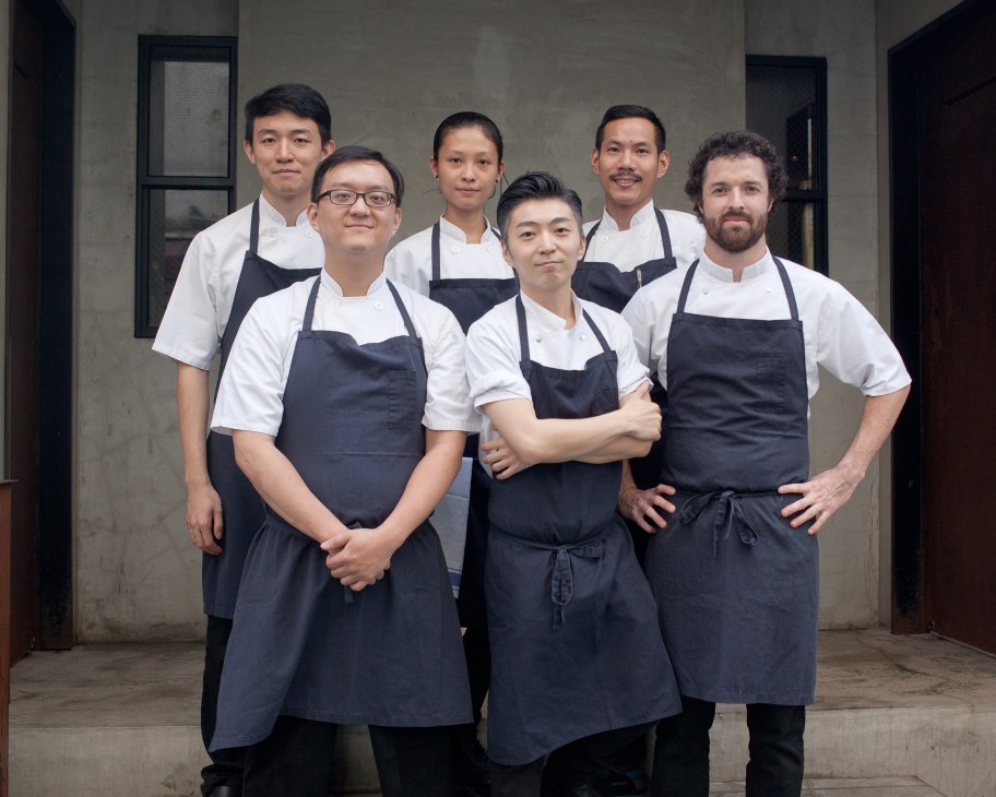Chef Richie Lin and his kitchen team stand together wearing white chef's coats and black aprons at Mume restaurant in Taipei.