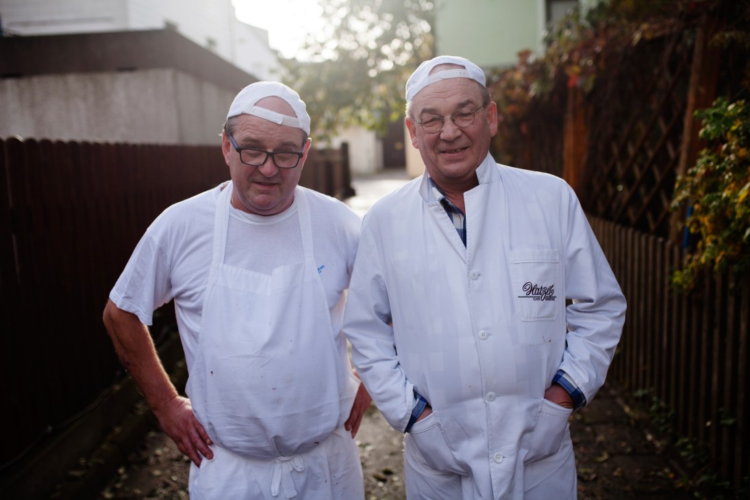 Two gingerbread makers in white uniforms and head coverings stand in an outdoor courtyard at Hatzel bakery in Selb, Germany.